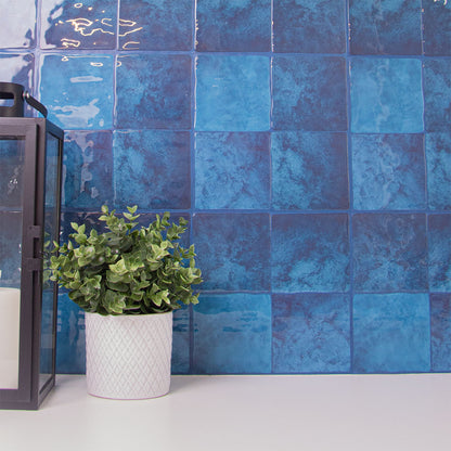 Blå fliseklistermærke i kvadratisk mønster brugt i bryggers over hvid bordplade.