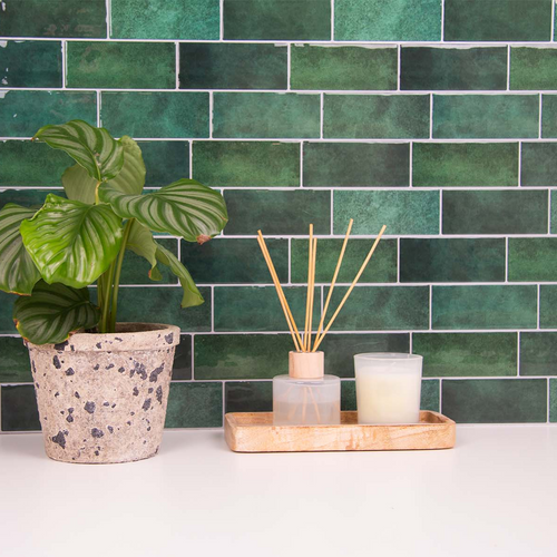 Grønne fliseklistermærker i metro mønster (jade journey) i bryggers med hvid bordplade. Pyntet med blomst og duftlys.