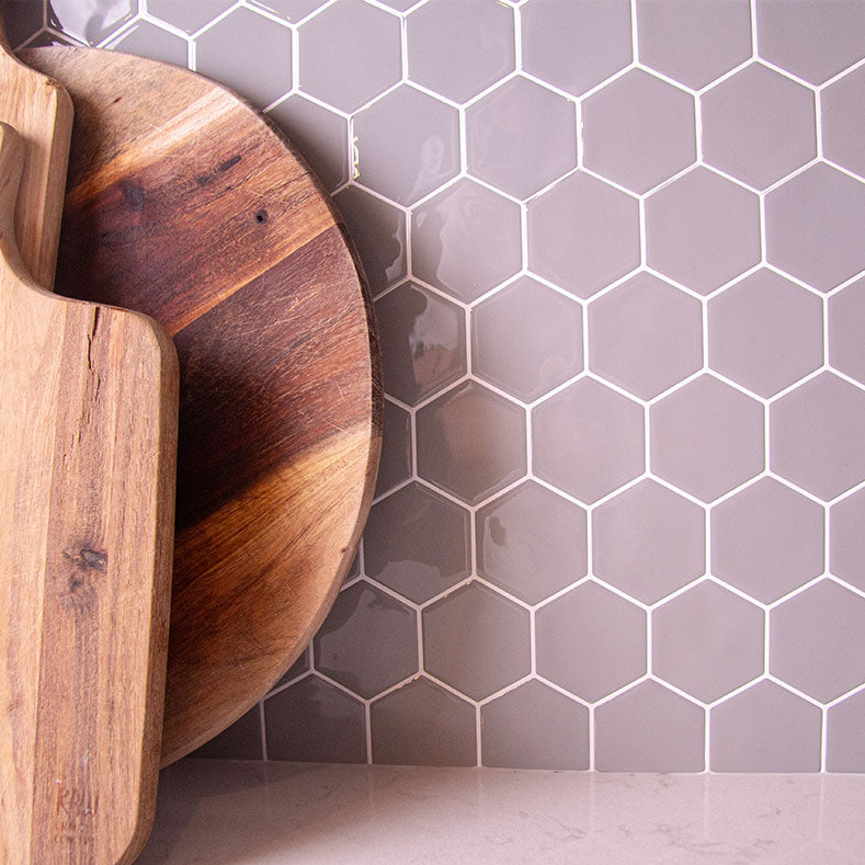 Grå fliseklistermærker i hexagon mønster brugt som backsplash i køkken.
