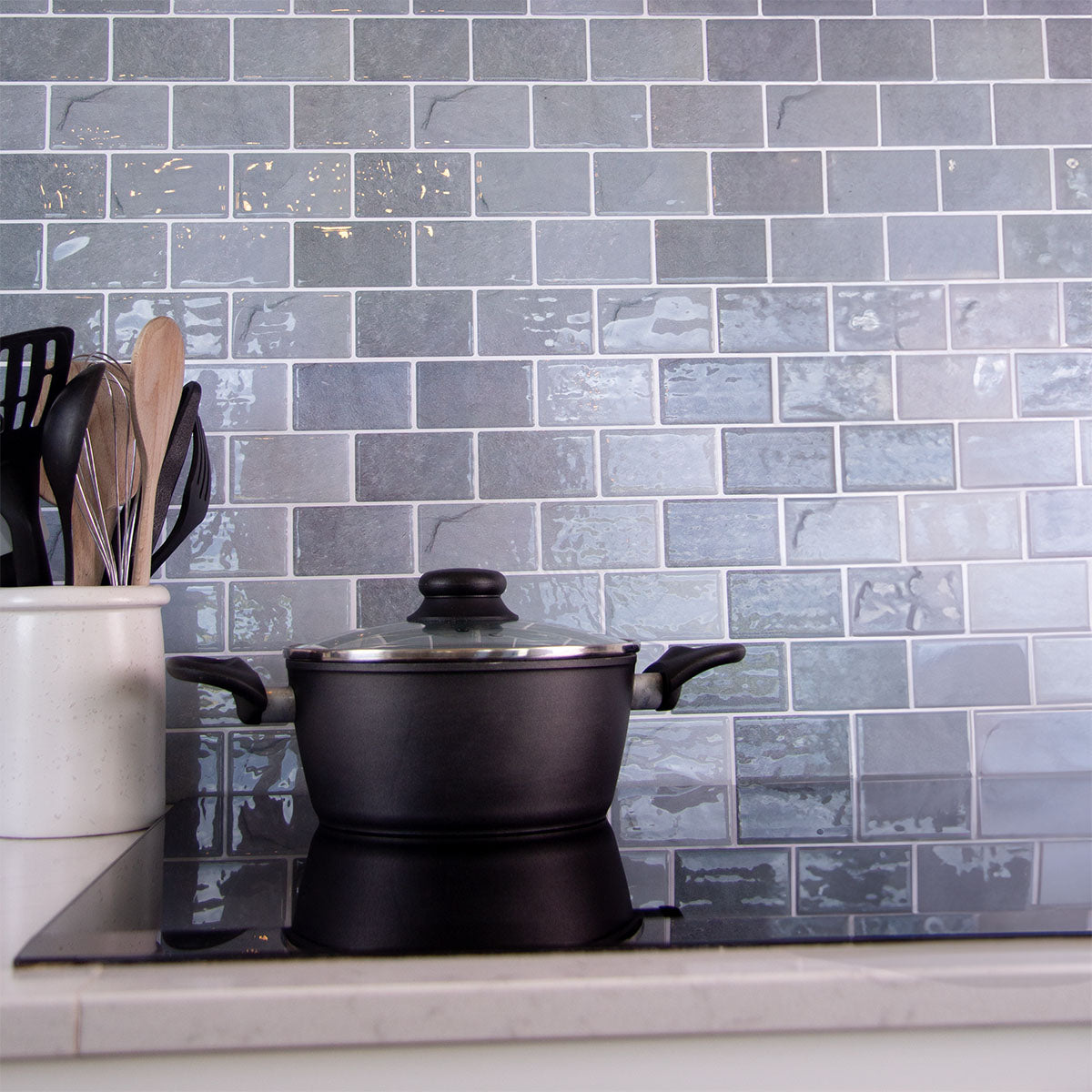 Grå fliseklistermærker der ligner marmor brugt i køkken bag kogeplade med en gryde.