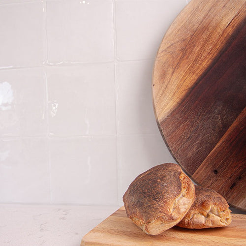 Hvide fliseklistermærker (pristine cube) i køkken med lys marmorbordplade pyntet med friskbagte boller.