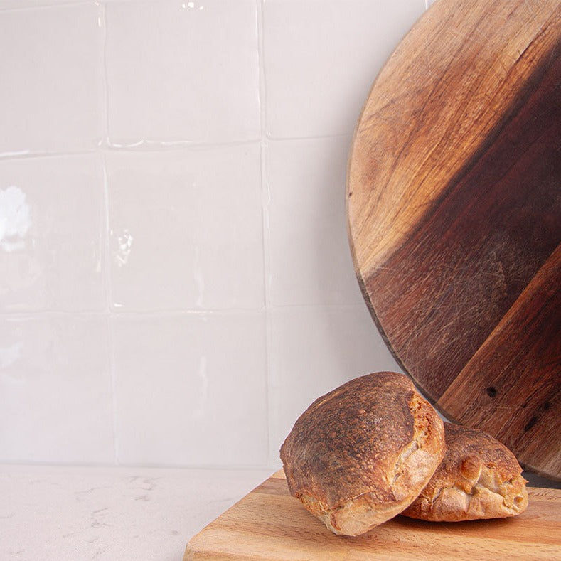 Hvide fliseklistermærker (pristine cube) i køkken med lys marmorbordplade pyntet med friskbagte boller.