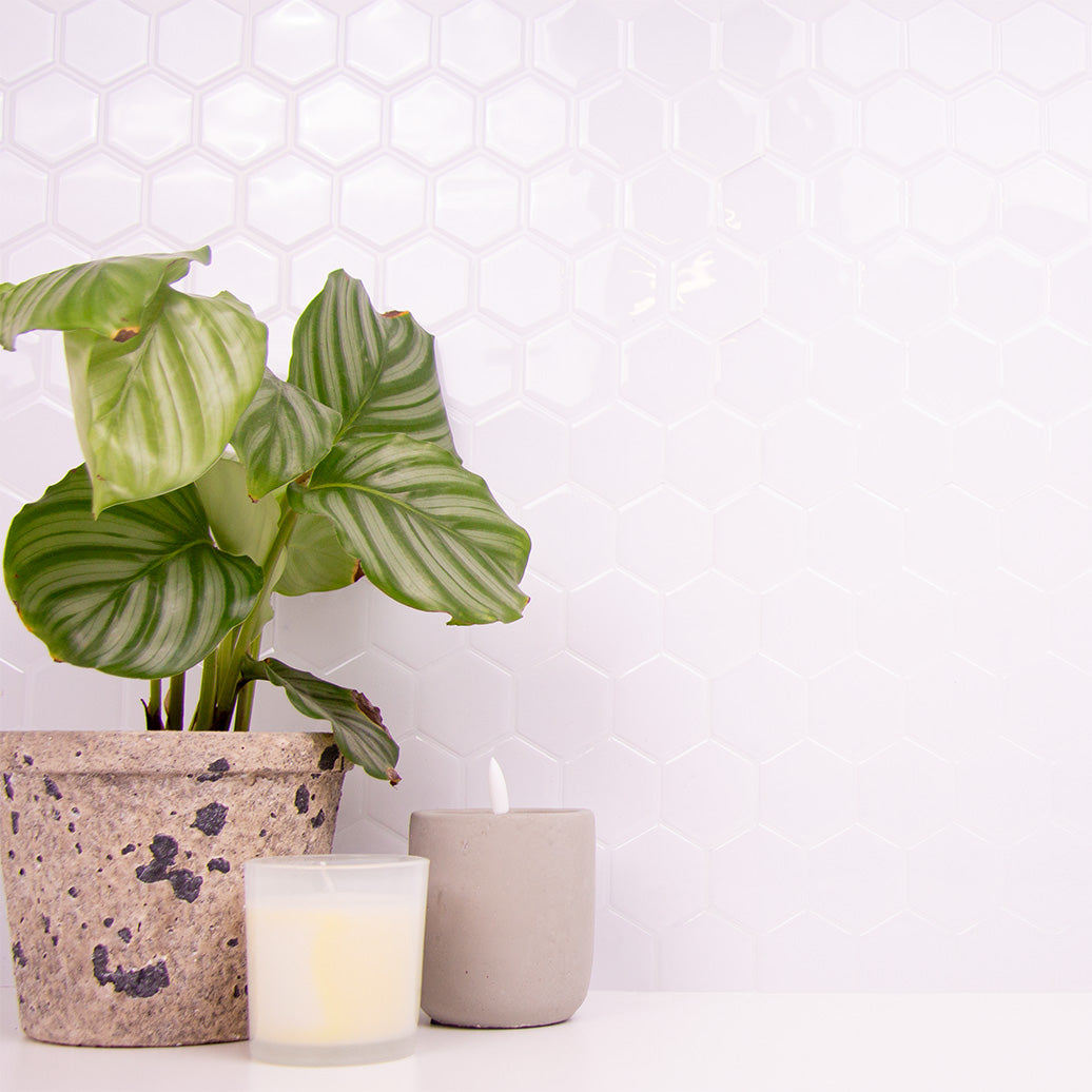 Hvid peel and stick flise (arctic hive) i bryggers med hvid bordplade dekoreret med plante og stearinlys.