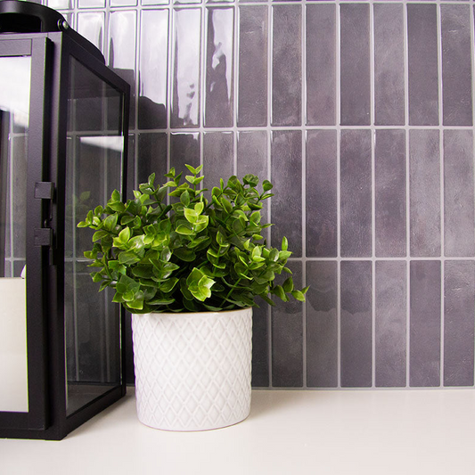 Sorte fliseklistermærker med mønster i lodrette rektangulære stave op mod hvid bordplade i et bryggers. 