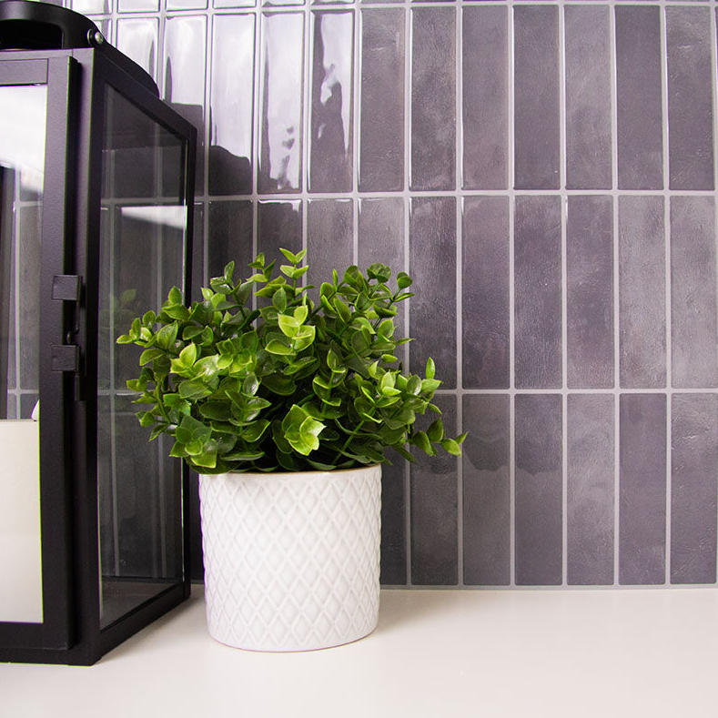 Sorte fliseklistermærker med mønster i lodrette rektangulære stave op mod hvid bordplade i et bryggers. 